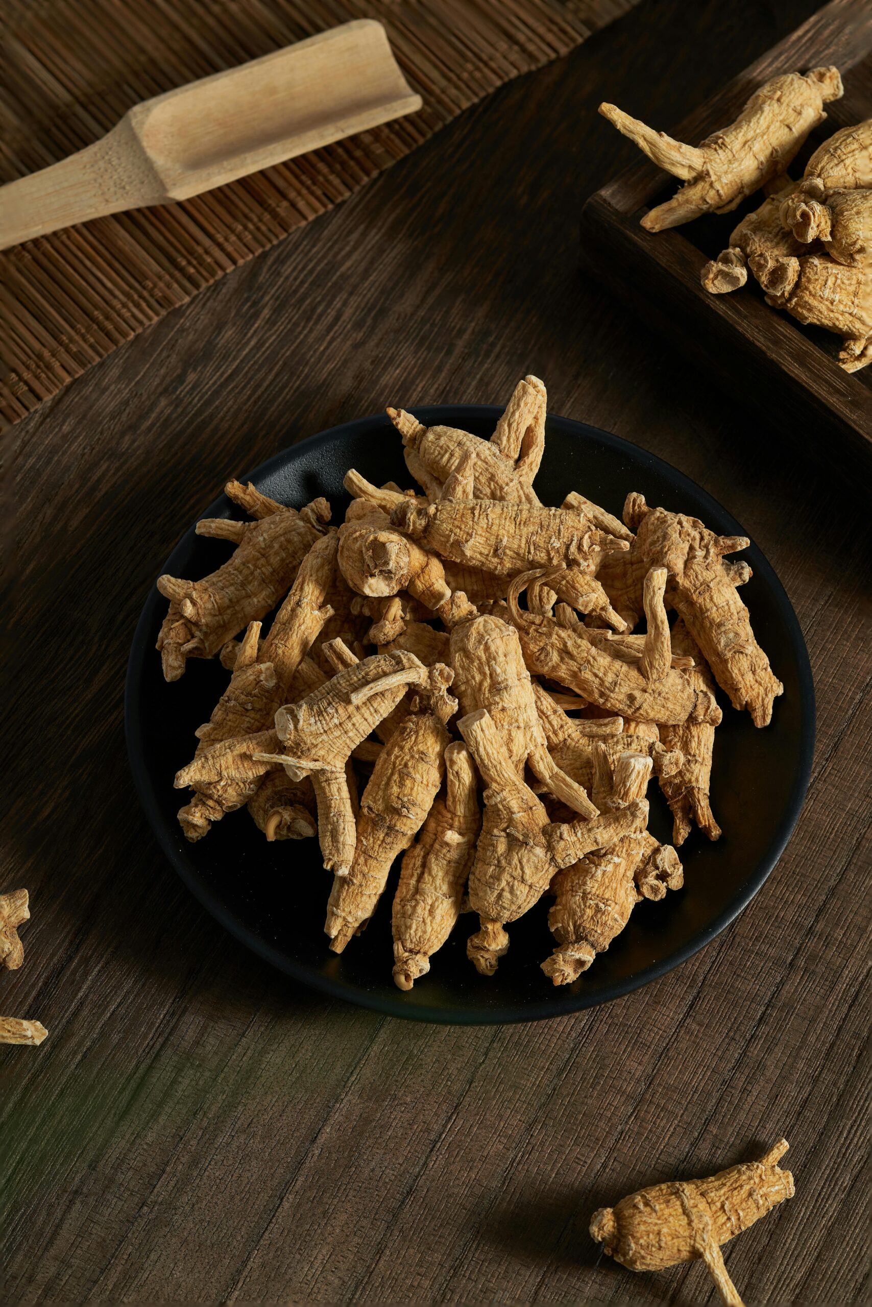 Detailed shot of dried ginseng roots on a dark plate for natural healing and cooking.